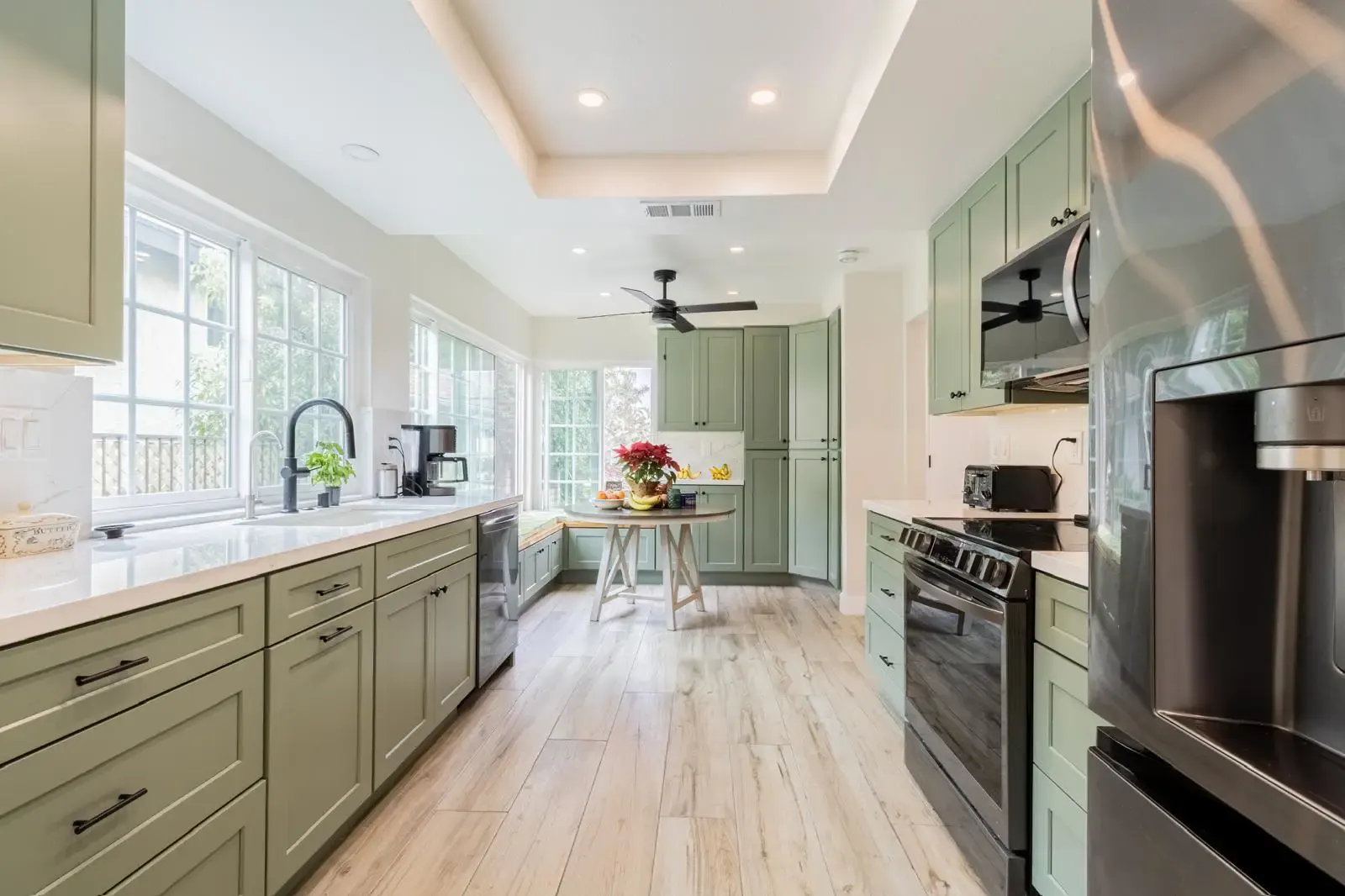 Sage-green shaker kitchen with white quartz counters, remodeled by Laguna Bay Developing in Orange County